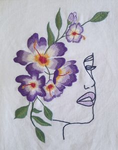 a woman's face with purple flowers in her hair on a white linen towel