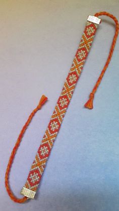 an orange and white beaded lanyard with two tassels on the end