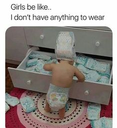 a baby in diapers is looking into an open drawer with blue blankets on it