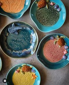 four plates with different designs on them sitting on a counter top next to shells and seashells