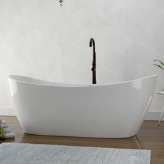 a large white bathtub sitting on top of a wooden floor next to a rug