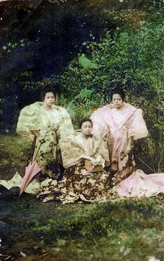 an old photo of three women in kimonos sitting on the grass with umbrellas