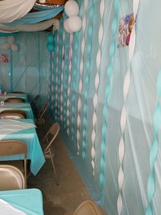 a room filled with lots of tables covered in blue and white cloths next to balloons