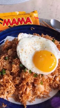 a blue plate topped with rice and an egg next to a packet of mamma