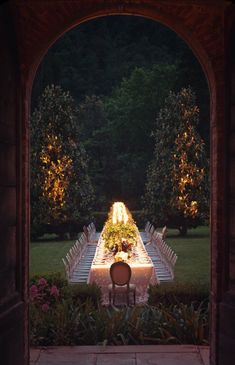 an outdoor dining table with chairs and lights on it is lit up in the evening