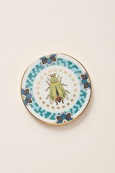 a blue and yellow plate with a bug on it's side, against a white background