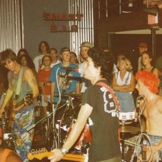 a group of young men standing next to each other in front of a microphone and guitar