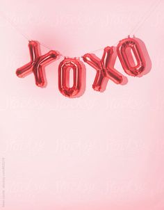 red foil balloons spelling the word tokyo hanging from a string on a pink background with white lettering