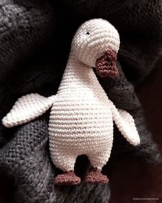 a knitted penguin sitting on top of a blanket