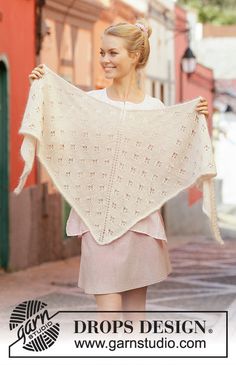 a woman is walking down the street holding a shawl