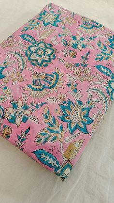 a pink and blue flowered cloth on top of a bed