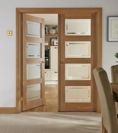 an open door leading to a kitchen and dining room with beige carpeted flooring