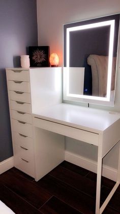 a white desk with a lighted mirror on top of it and drawers below the desk