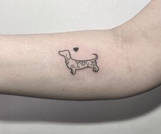 a small black and white dog tattoo on the left arm with a heart in it