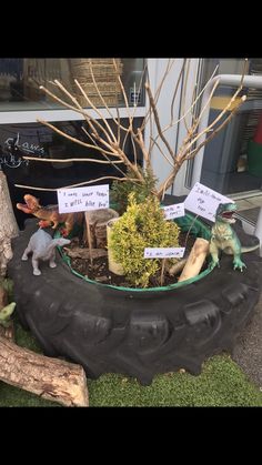 there is a planter that has dinosaurs in it and signs on the tree stumps