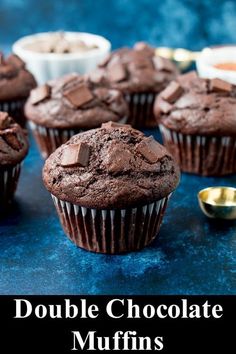 several chocolate muffins are sitting on a blue surface