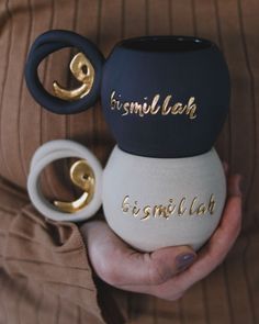 a person holding two mugs in their hands with the words bismill lab on them