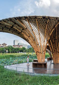 an outdoor covered area with lots of green plants and people walking around it in the distance