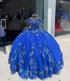 Make a grand entrance in this Royal Blue Ball-Gown Quinceañera Dress. This dress is crafted from layers of luxurious tulle and flows elegantly into a chapel train, adding to its regal charm. The off-the-shoulder neckline and sweeping ball gown silhouette create a majestic look, perfect for a special celebration. The exquisite appliques and shimmering beading embellish the bodice and skirt, enhancing the gown with intricate details and a touch of sparkle. The lace-up back allows for a beautifully Dark Quinceanera Dresses, Royal Blue Quince Dress, Blue Quince Dress, Dream Quinceanera, Royal Blue Ball Gown, Royal Blue Quinceanera Dresses, Royal Blue Quince, Royal Blue Quinceanera, Quince Dresses Blue