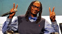 a man with dreadlocks sitting in a chair and holding up two peace signs