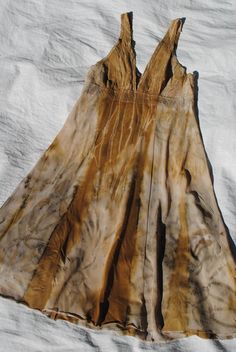 a dress is laying on a white sheet with brown and tan dyes in it