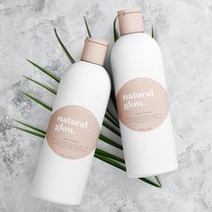 two bottles of natural glow body lotion on a marble surface