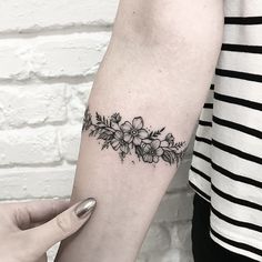 a woman's arm with flowers and leaves tattoo on the left side of her arm