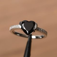 It is a natural black spinel ring. The main stone is 8mm*8mm heart cut, weight about 2.33 carats. The basic metal is sterling silver and plated with rhodium. To change the metal to a solid gold (white/rose) or platinum is also available, please ask for a quotation if you want. You can also go to my shop Home for more elegant rings: https://www.etsy.com/shop/godjewelry?ref=hdr_shop_menu More black spinel rings: https://www.etsy.com/shop/godjewelry/items?ref=seller-platform-mcnav&section_id=21 Black Heart Cut Jewelry For Wedding, Black Heart-shaped Jewelry For Anniversary, Valentine's Day Black Diamond Jewelry, Black Heart-shaped Diamond Jewelry, Black Heart-shaped Gemstone Jewelry, Black Heart-shaped Promise Jewelry, Elegant Black Heart Ring For Weddings, Black Diamond Heart-shaped Jewelry, Elegant Black Rings For Valentine's Day