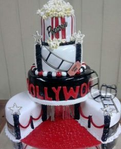 a three tiered cake with movie themed decorations on the top and red carpet underneath