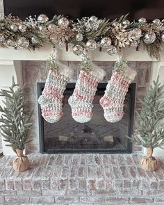 christmas stockings hanging from a mantel over a fireplace with pine cones and silver baubs