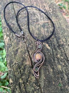 a wire wrapped necklace on top of a piece of wood