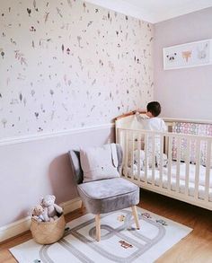 a small child standing on top of a chair next to a crib in a room