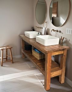 two sinks and mirrors in a bathroom with wood flooring on the walls, along with wooden stools