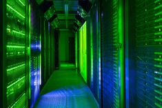 rows of servers in a data center with green and blue lights shining on them,