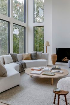 a living room filled with lots of furniture next to large windows and a fire place