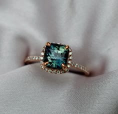 an engagement ring with a blue diamond surrounded by white and brown diamonds on a cloth