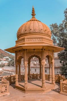 an ornate gazebo sits in the middle of a desert area with mountains in the background