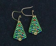 a pair of green beaded christmas tree earrings next to a quarter penny on a black surface