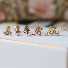 five different types of rings sitting on top of a white box with pink flowers in the background