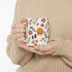 a woman is holding a coffee mug in her left hand and wearing a beige sweater