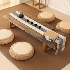 a coffee table with four stools and a tea pot on it in the middle of a room