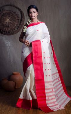 This stunning red and white cotton saree is a traditional Bengali style known as the dhaniakhali saree. Made from high-quality cotton and finished with a stiff starch, this saree is perfect for any formal occasion. The intricate white designs on the red background make for a bold and eye-catching look. Add this saree to your collection for a timeless piece that will never go out of style. Color : Red and Off White .  Blouse Piece : No.  Fall Pico : Yes.  Care : Dry-Clean Only. Red Cotton Saree For Wedding, White Cotton Saree With Zari Work, White Cotton Silk Saree For Puja, White Traditional Wear With Traditional Patterns For Rituals, White Cotton Saree With Cutdana, White Cotton Silk Traditional Wear For Ceremonies, White Cotton Saree With Traditional Drape, Traditional White Cotton Silk Saree, White Cotton Dupatta With Self Design