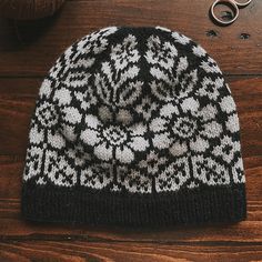 a black and white knitted hat sitting on top of a wooden table next to scissors