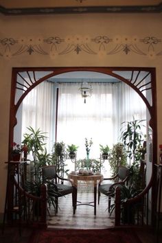 an arched doorway leading to a dining room with potted plants