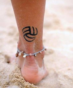 a person with a tattoo on their foot in the sand