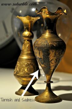 two gold vases sitting next to each other on top of a white countertop