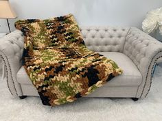 a couch with a crocheted blanket sitting on top of it next to a lamp