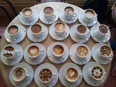 a table topped with lots of different cups of coffee next to each other on saucers