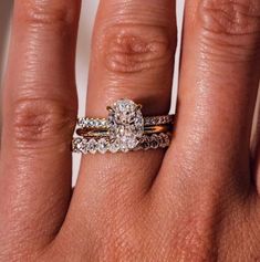 a woman's hand with two wedding rings on her left and an engagement ring on the right