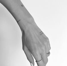 black and white photograph of a woman's hand with tattoos on her left wrist